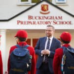 students and headteacher in front of their school